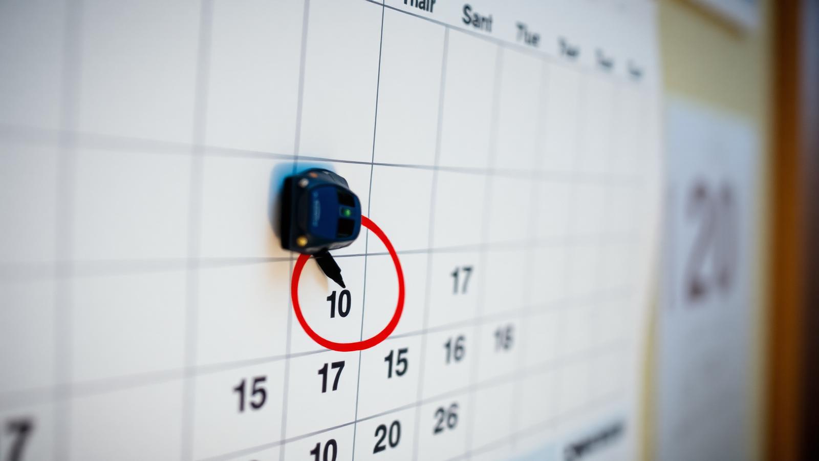 Calendar with a date circled in red marker and a small toy car sitting on top