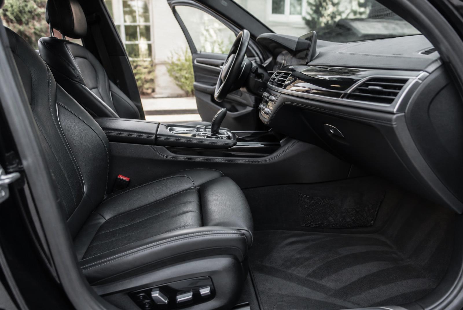 Freshly detailed luxury car interior with spotless black leather seats, gleaming dashboard and vacuum lines on charcoal carpet